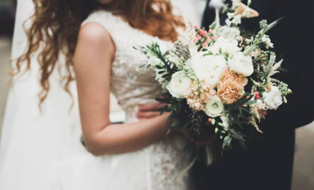 Beauty wedding bouquet with different flowers in hands
