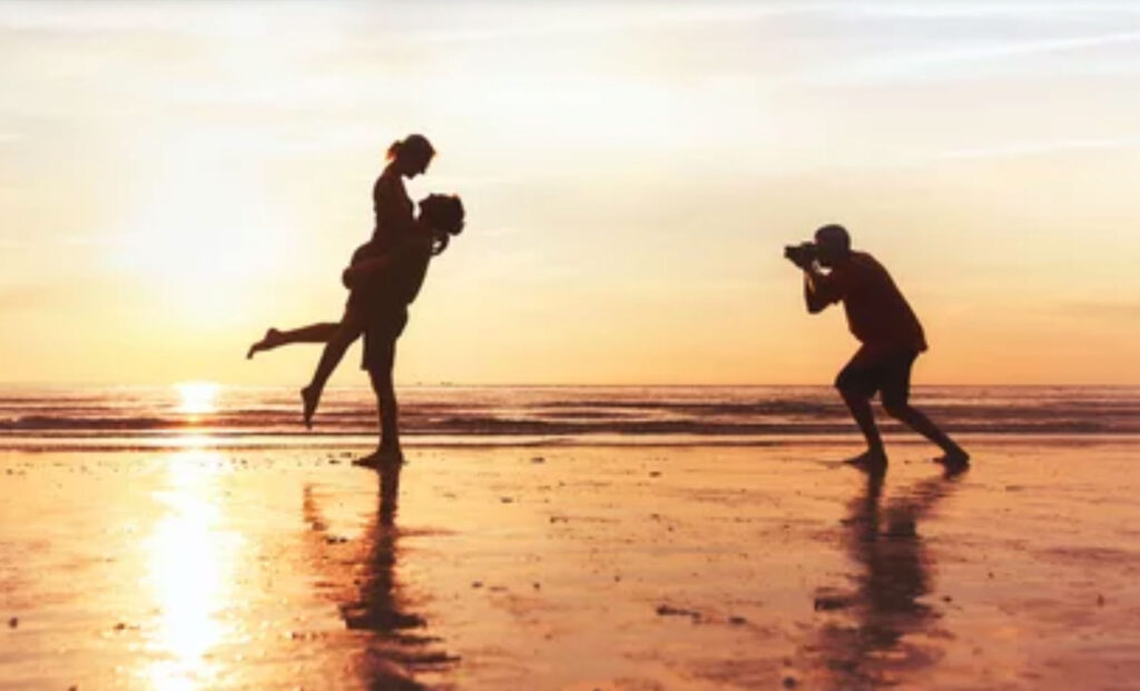 photographer working with couple on the beach, professional wedding photography
