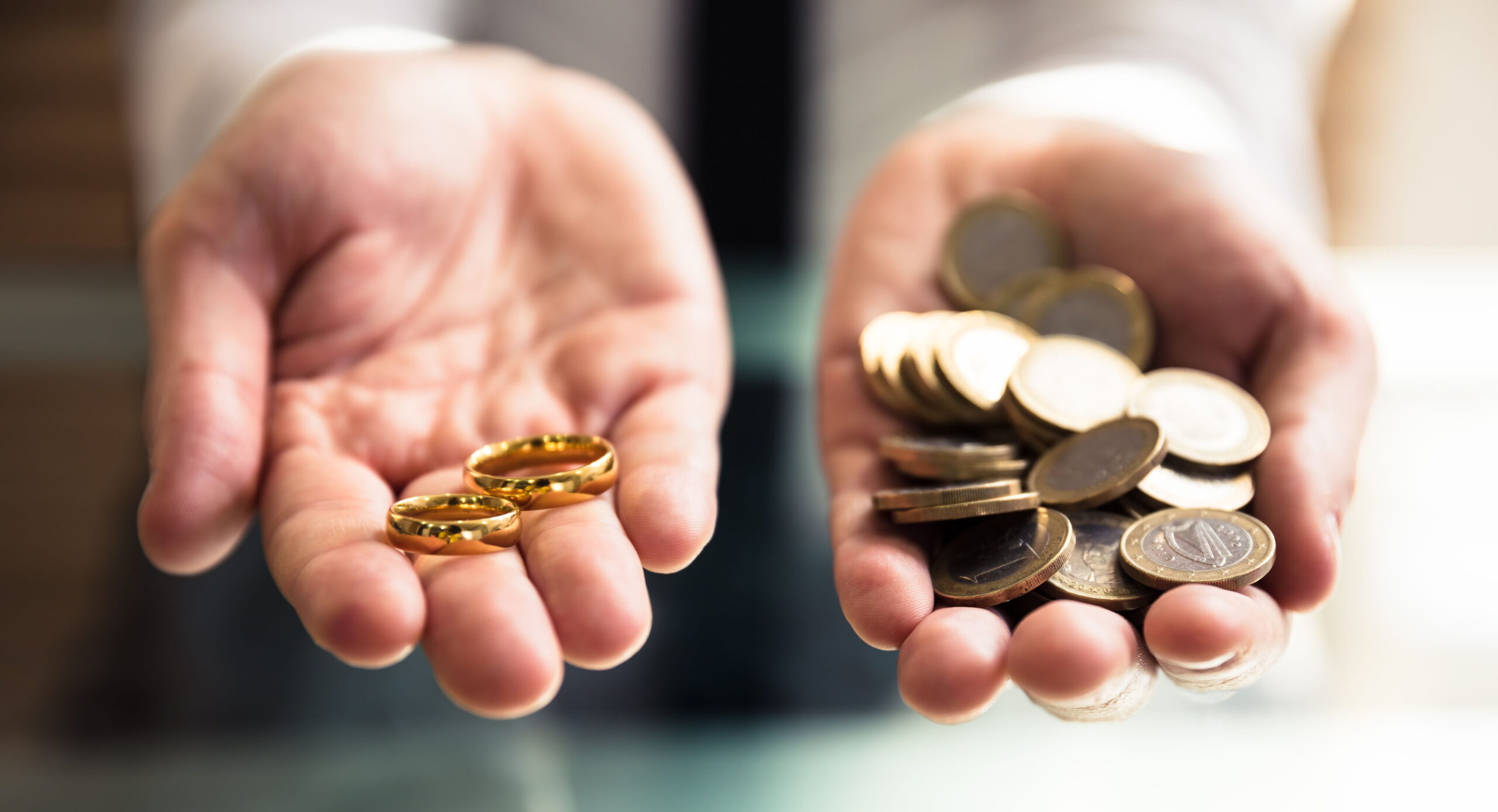 Close-up Of A Person's Hand Holding Wedding Rings And Golden Coins