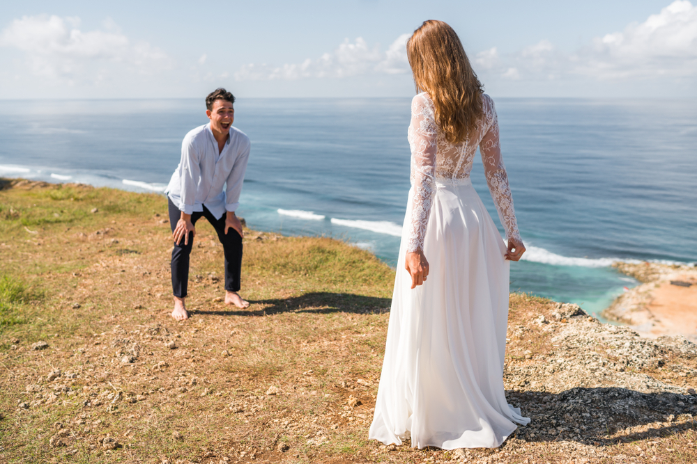 Groom enjoys looking at his wife to be on cliff near ocean