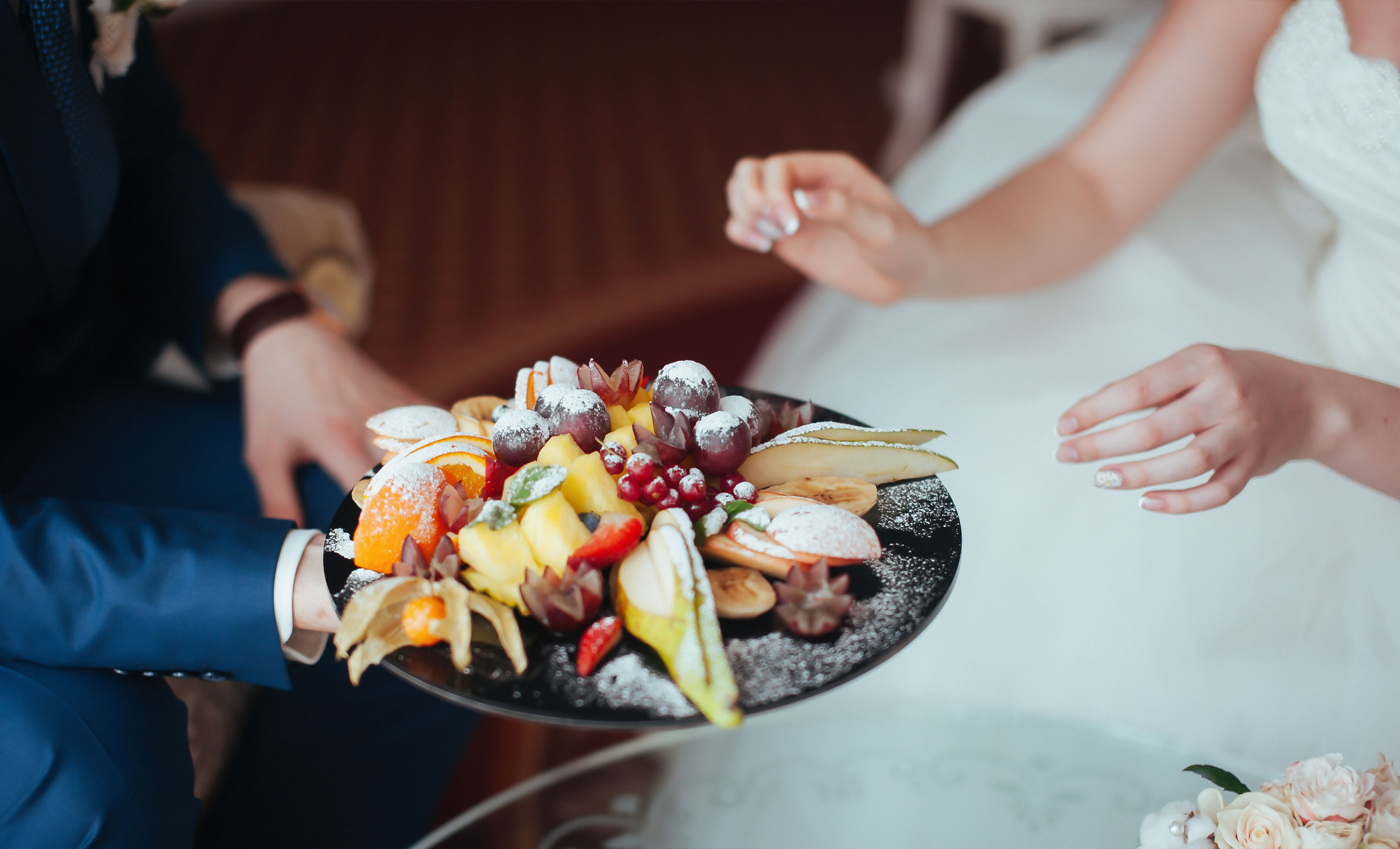 The bride and groom eat fruit dessert at the wedding