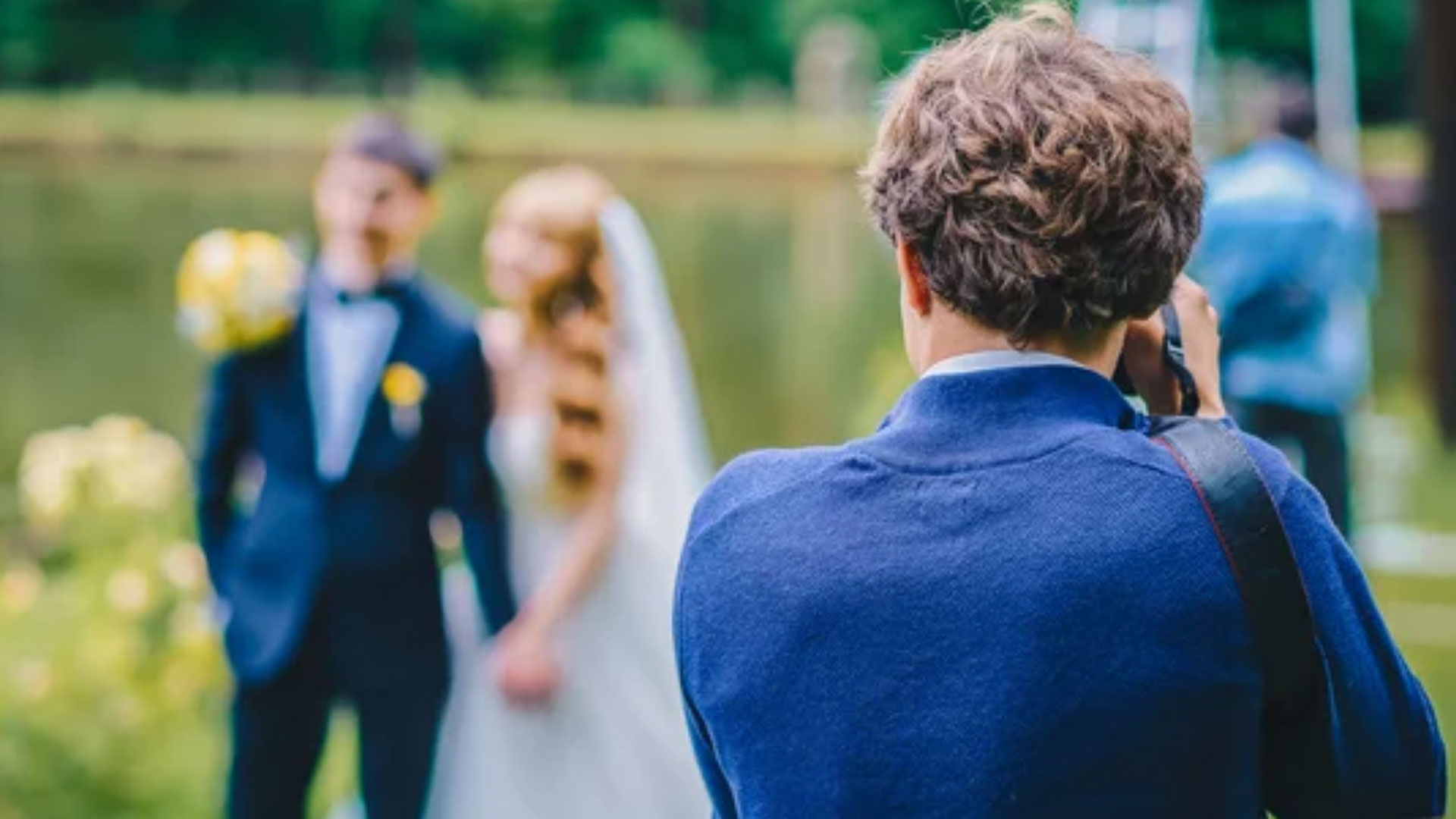 A wedding photographer takes pictures of the bride and groom in nature, the photographer in action